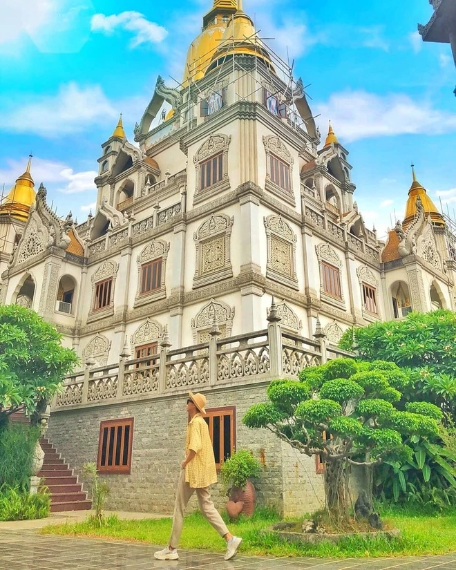 Khách du lịch mặc áo vàng dạo bước trước công trình kiến trúc chạm khắc tinh xảo tại Chùa Bửu Long Quận 9